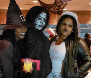 Four female guests are in Halloween costumes and pose for a photo on the Halloween Costume Party Cruise on the Riverboat.