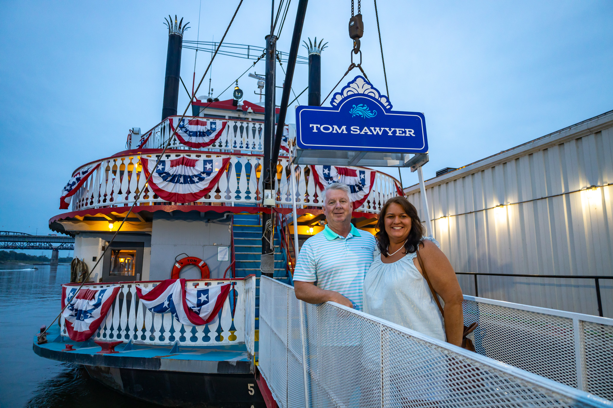 A couple poses for a photo in front of the Tom Sawyer riverboat before a Skyline Dinner Cruise.