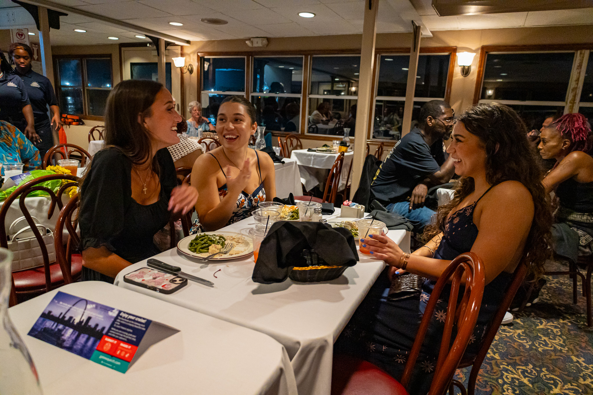 Three women laughing and chatting while they eat on a Skyline Dinner Cruise.