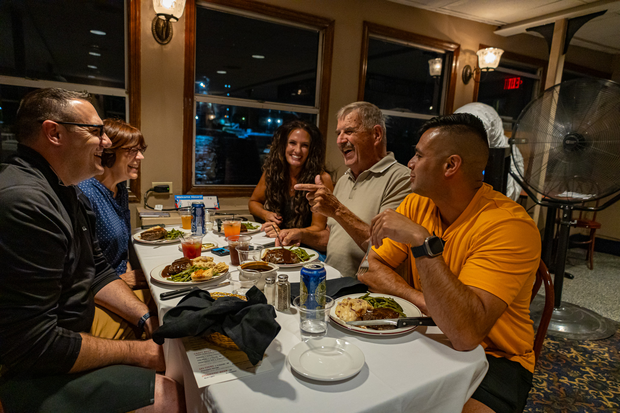 A family laughing and chatting while they eat on a Skyline Dinner Cruise.