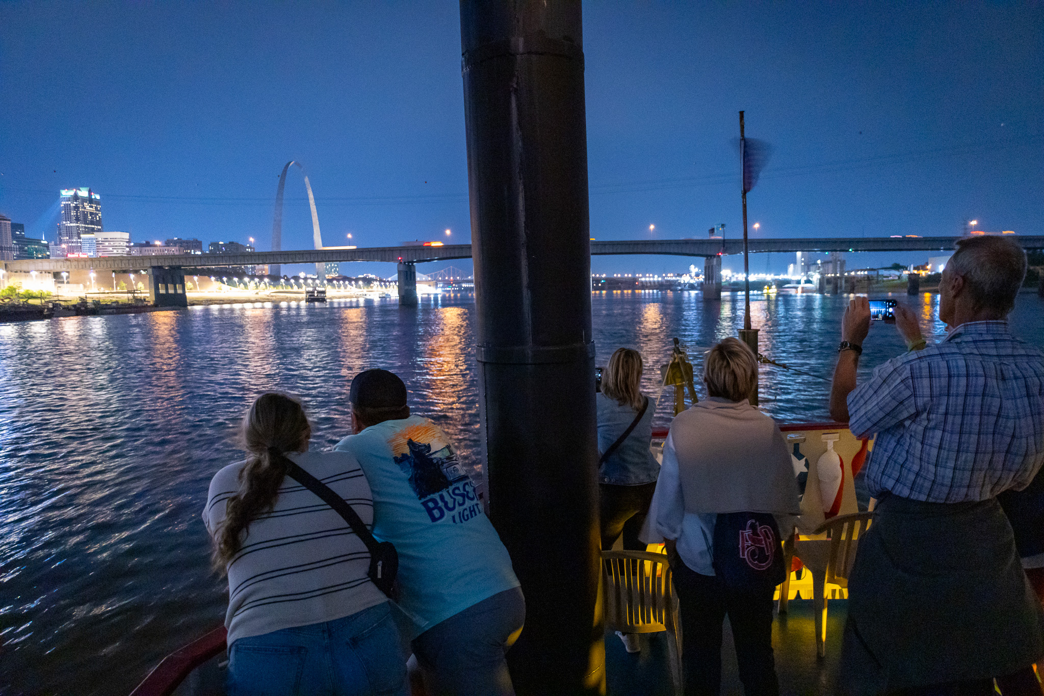 Groups of guests on a Skyline Dinner Cruise enjoy a beautiful evening view of downtown St. Louis from the top deck of the riverboat.