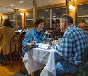 Two happy guests smiling while they eat on a Skyline Dinner Cruise.