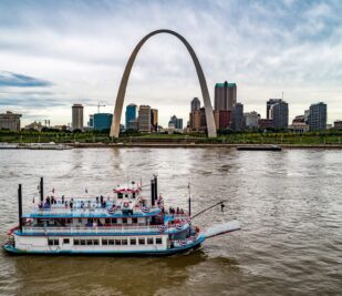 The Tom Sawyer riverboat cruises down the Mississippi River in St. Louis with dozens of passengers on board.